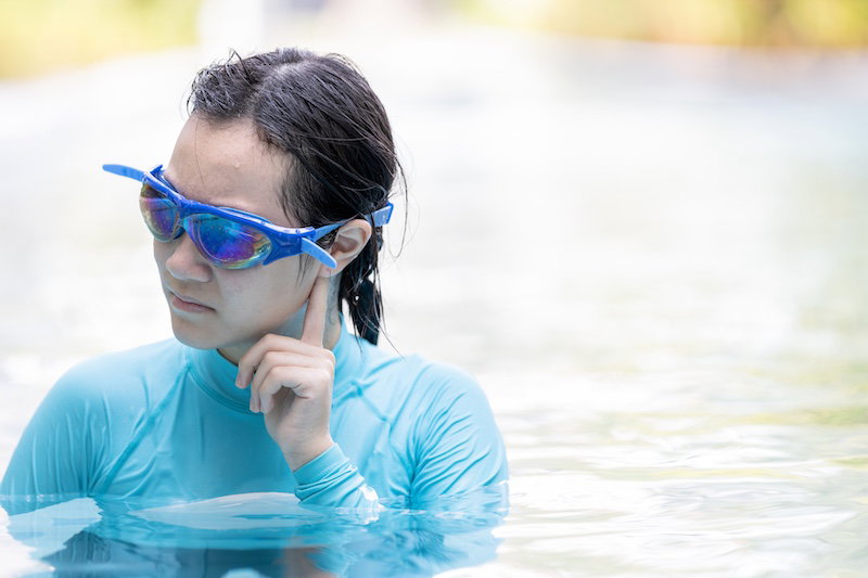 Stressed asian girl had tinnitus,problem with water entering the ear canal while swimming,female people cleaning ears after diving in swimming pool,otitis externa,swimmer's ear,health care concept