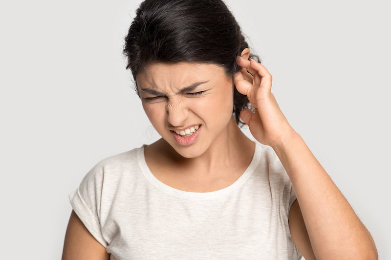 Dissatisfied young ethnic woman isolated on grey studio background cover ears annoyed by loud noise, unhappy millennial indian girl bothered by noisy sound, suffer from painful unpleasant feeling