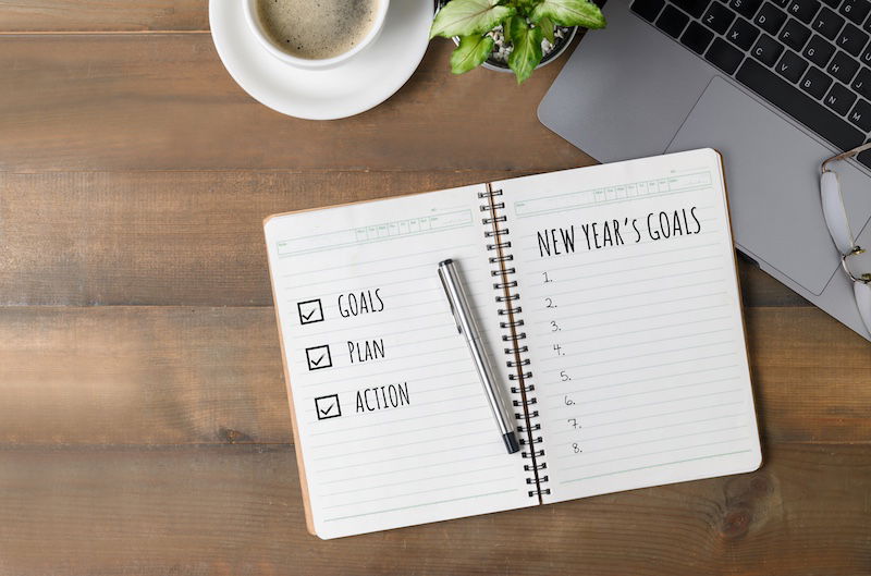 Hand man writing New year's goals on note paper with coffee and laptop, Business motivation and inspiration conceptual